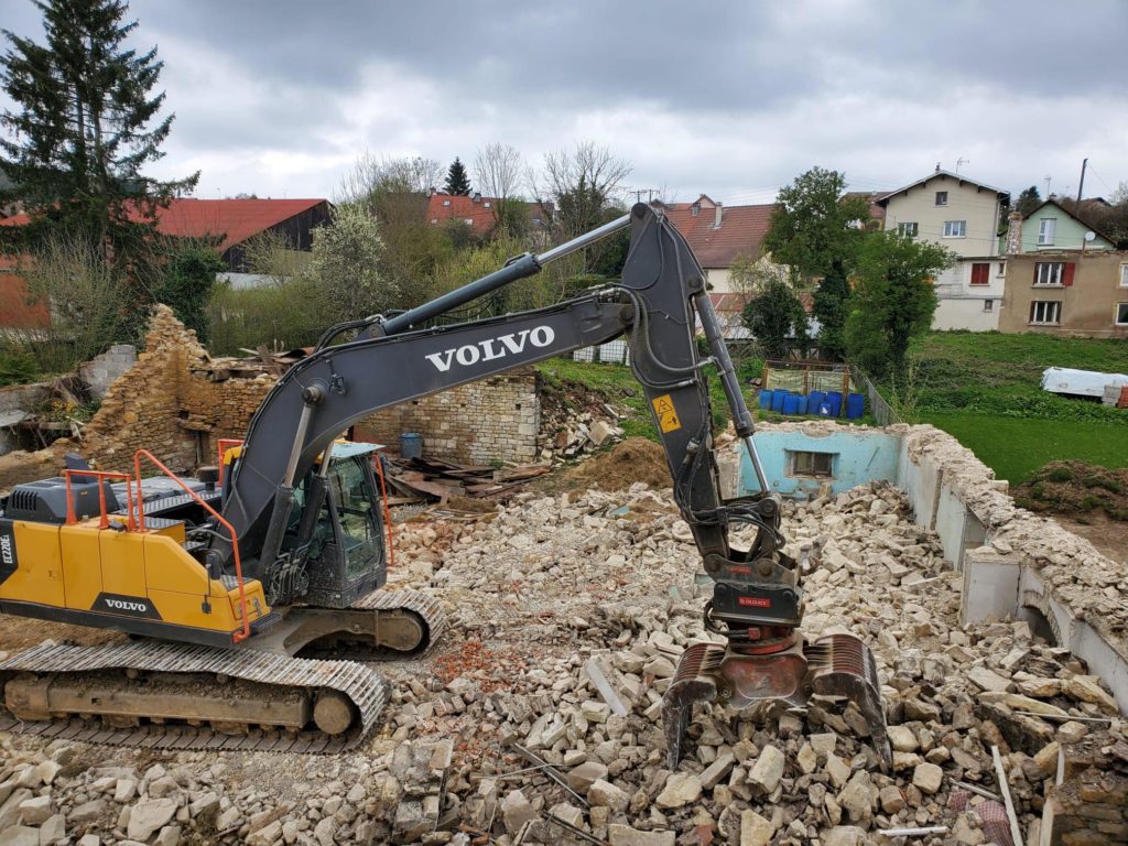 Pelle Volvo démolissant une maison, gravats au premier plan