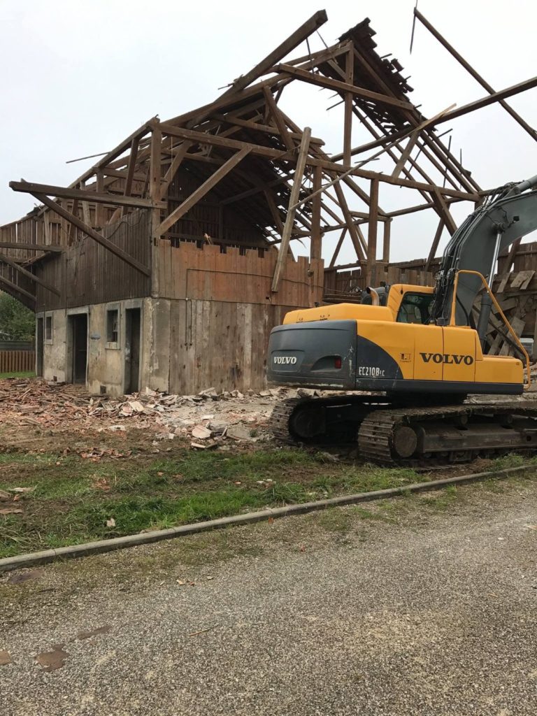 Pelle Volvo devant la charpente de la grange en démolition à Spechbach-le-Haut