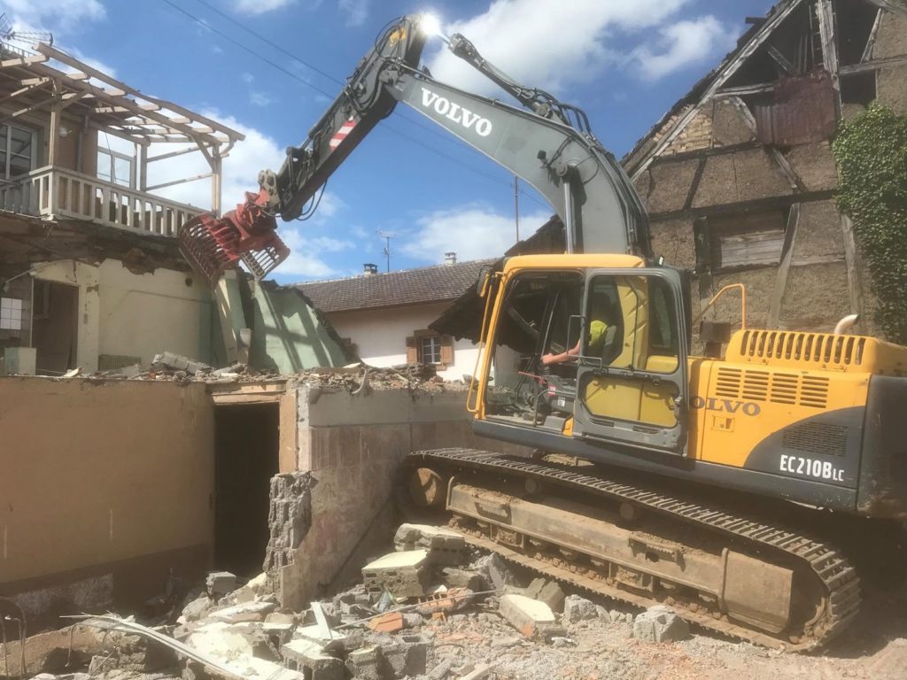 Pelle Volvo équipée d’une pince démolissant un bâtiment à Carspach